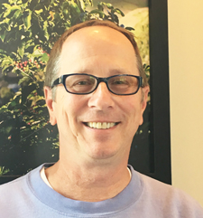 A man with glasses smiling for the camera.